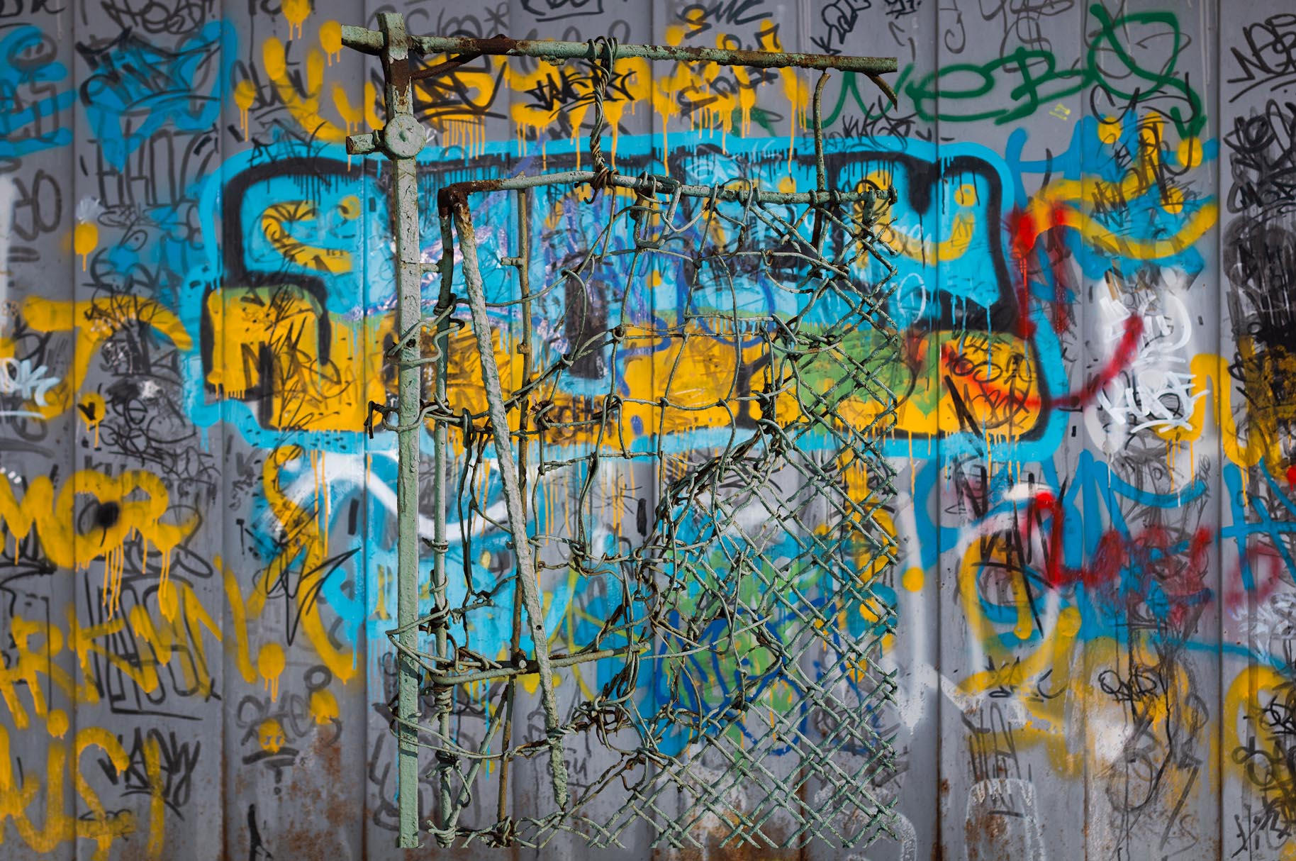 A broken fence from 1930s collaged over a soviet garage covered in graffity