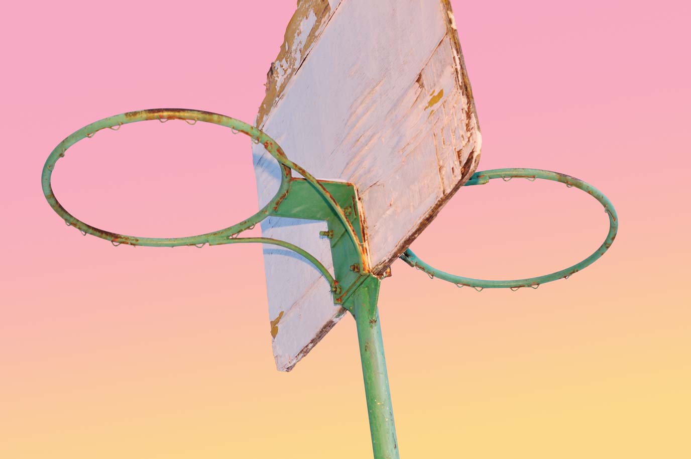 Two basketball rings mounted on a single pole over the pink background